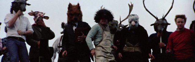 screenshot from the Wicker Man, of figures on a hillside wearing animal masks
